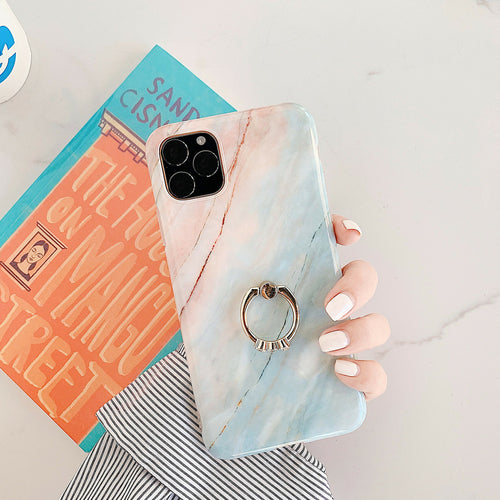 Phone case with ring holder held by a hand on a light surface