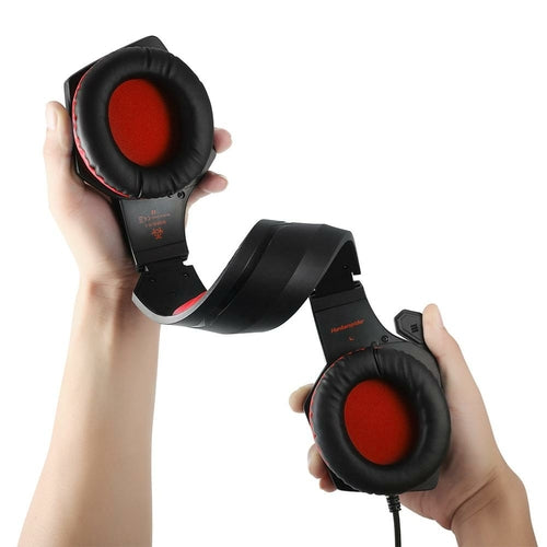 Black gaming headphones with red interior being held by a person on a white background